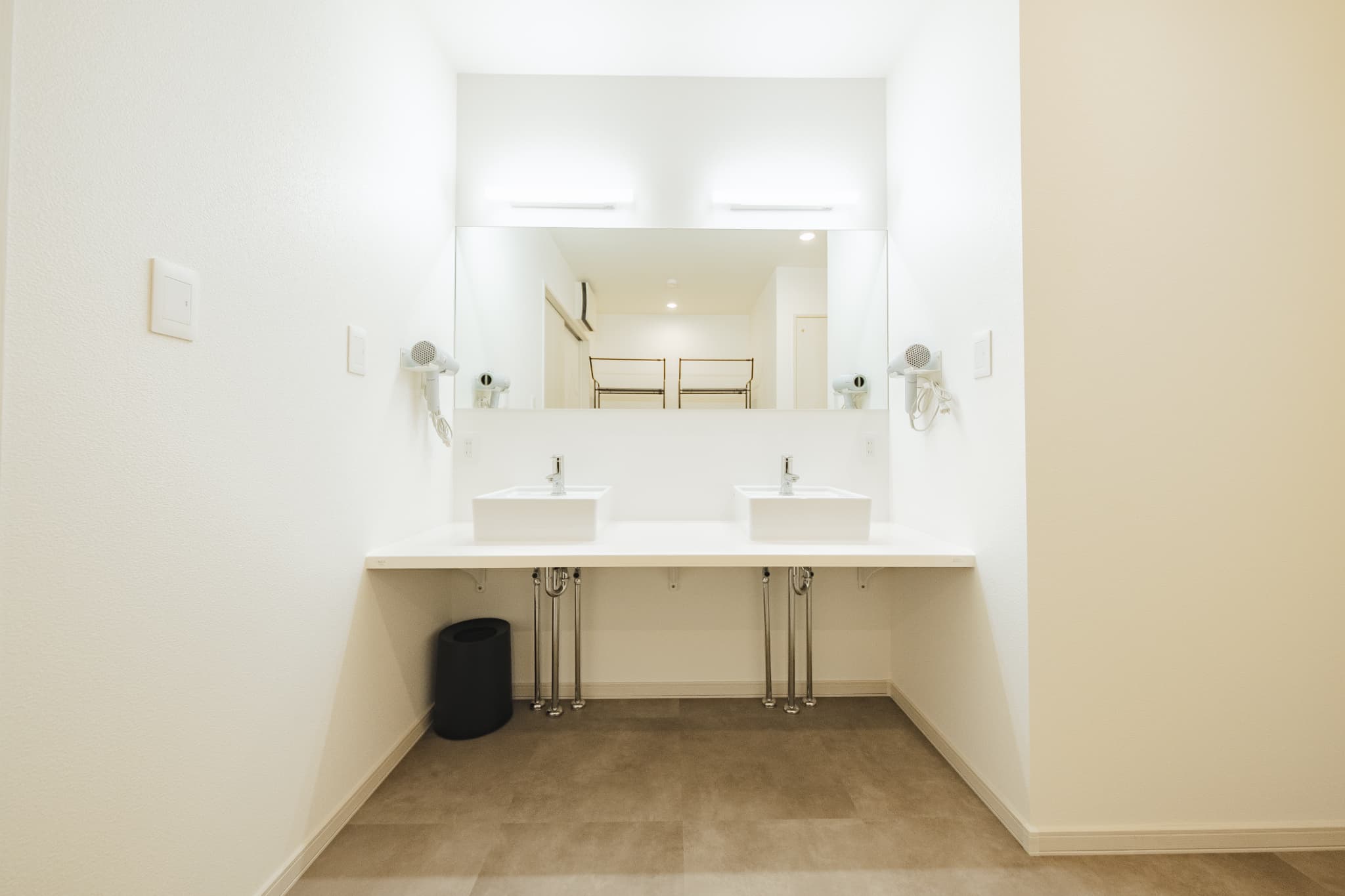 ダブルボウルの洗面台を備えたホテル仕様の洗面スペース。白を基調とした清潔感のあるデザインで複数名利用に対応。