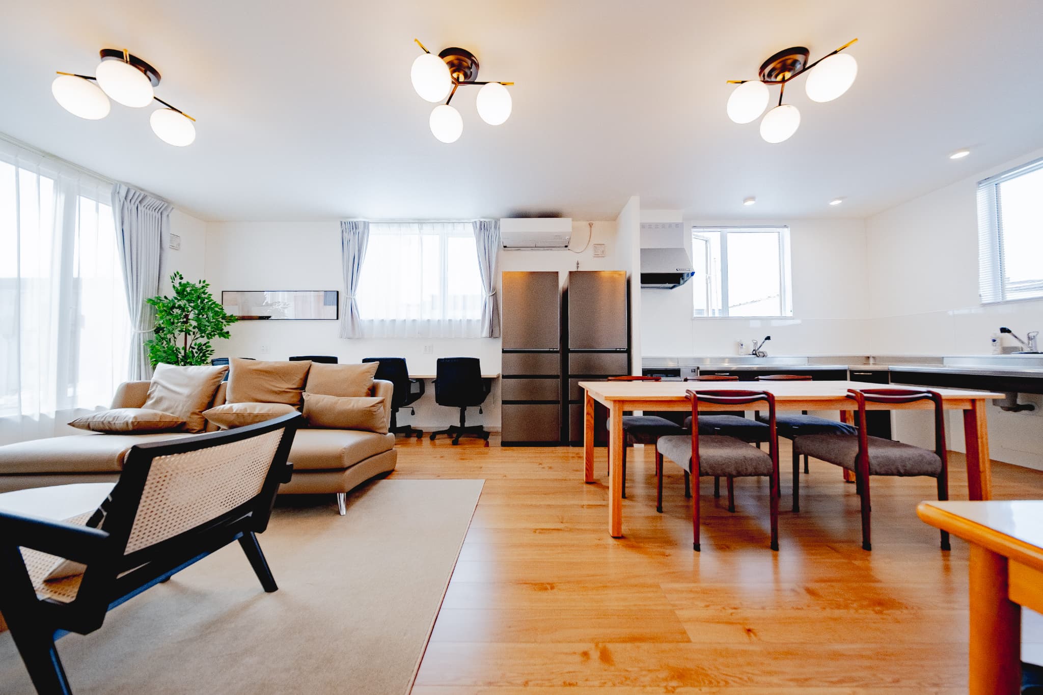 広々としたLDKに大型窓を配置し、自然光を取り込む明るい空間。木目フローリングと白壁を基調に、ソファとダイニングセットを配置。